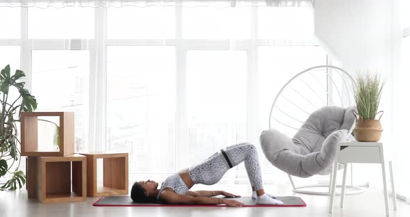 Athletic black woman engaged in sports performs stretching exercises with elastic bands.