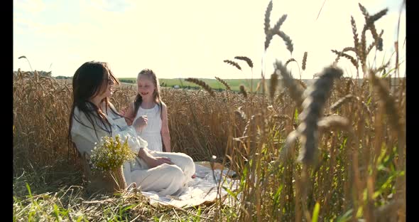 Beautiful Mother and Daughter Having Fun in a Wheat Field on Sunset