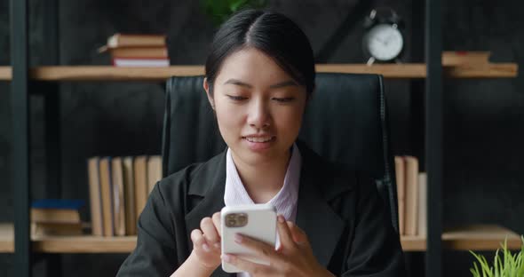 Professional Asian Businesswoman Holding Modern Smartphone Texting Message in Office