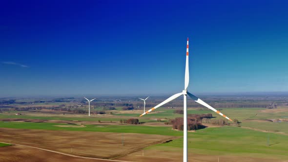 Aerial view of white wind turbine with blue sky on farm field