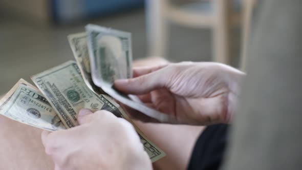 Men's Hands Count Cash Dollars and Other Currencies at Home in a Bright Room