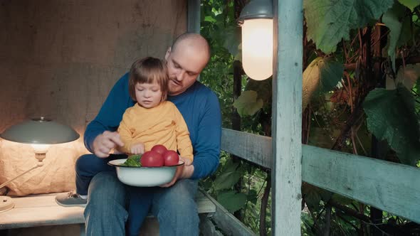 Father and Small Child Eat Fresh Organic Vegetables From Farm Sitting on Porch