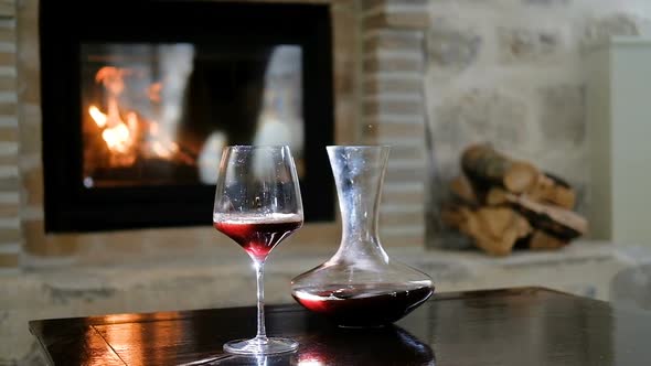 Glass and carafe with red wine on the background of the fireplace