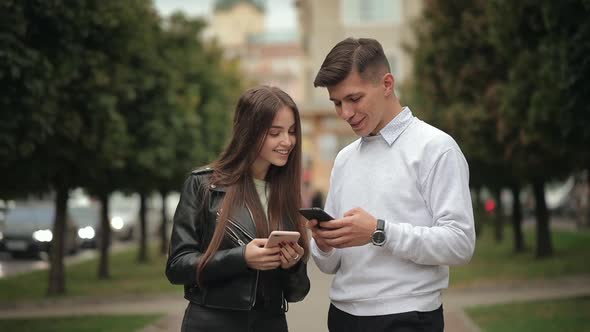 A Young Woman and a Man are Exchanging Information on Smartphones