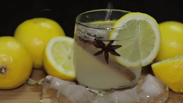 Pours Lemon Juice Into Glass with Ice, Thyme and Lemon Slices