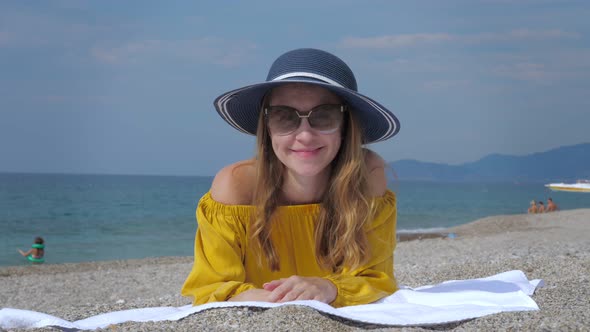 Positive Female Tourist in Sunglasses and Hat on Sea Beach
