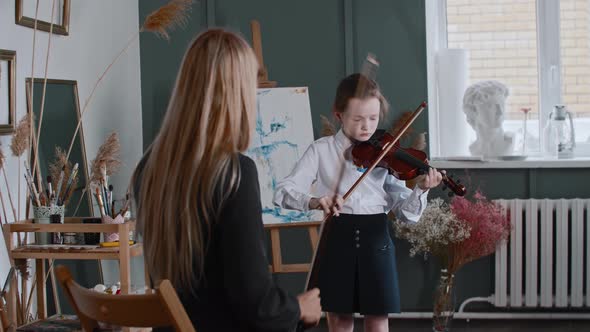 A Girl Learning Playing Violin with Her Blonde Woman Teacher in the Class
