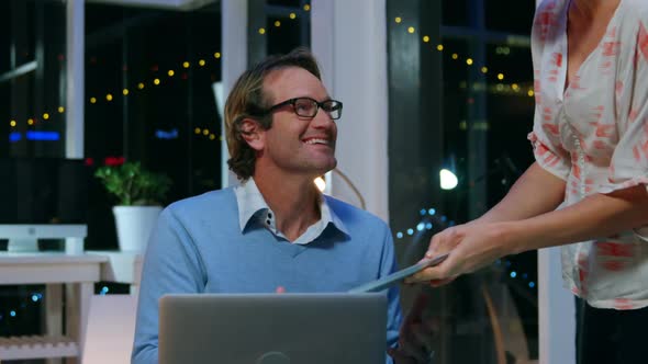 Businesspeople discussing over digital tablet in office