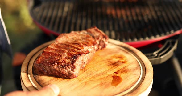 Man put down meat on a wooden board ready to eat grilled steak meat,