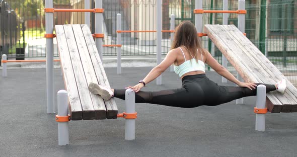 Woman Is Doing Cross Twine Between Two Inclined Benches on Sport Ground.