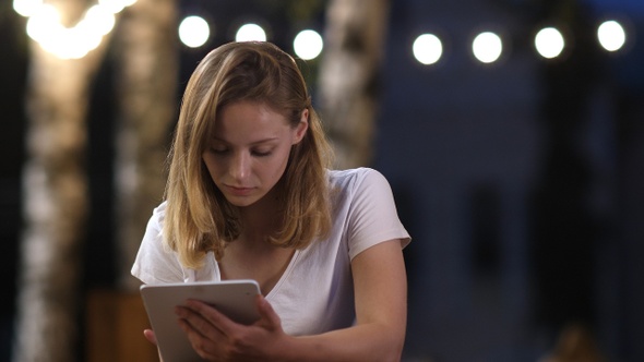 Teenage Girl Using a Tablet Sitting in Outdoor Cafe