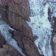 Aerial view over waves breaking onto rocks in the ocean - VideoHive Item for Sale