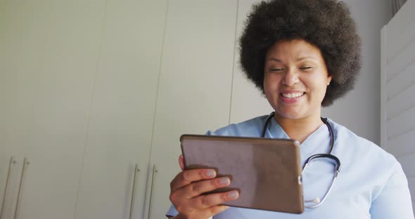 Video of happy plus size african american female doctor using tablet