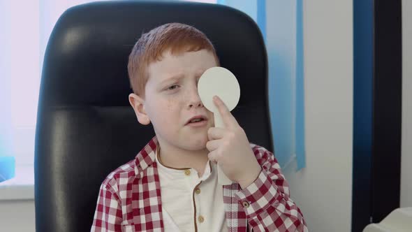 A Redhaired Boy in a Plaid Red and White Shirt in the Ophthalmologist's Office at the Optics Clinic