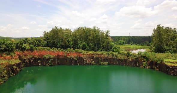 Beautiful emerald lake within a hole in the mountain, in the background a lot of vegetation and a ri