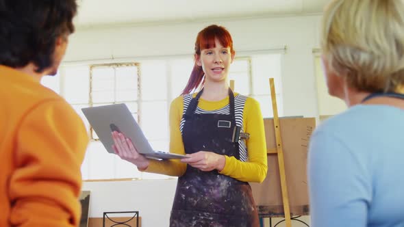 Woman interacting with artists while using laptop 4k