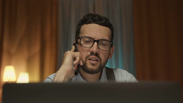 Close Up Shot of a Cheerful Man in Glasses Sitting at the Office Desk Talking on the Phone