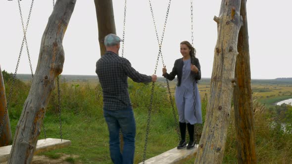 Boy and Girl Swinging on a Swing Opposite Each Other in a Beautiful Place