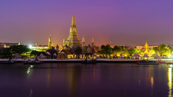 night to day time lapse of Wat Arun Temple with Chao Phraya river in Bangkok, Thailand