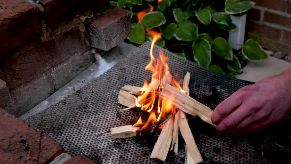 Man stokes small fire using kindling
