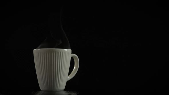 Cup of hot drink with steam on a dark background.