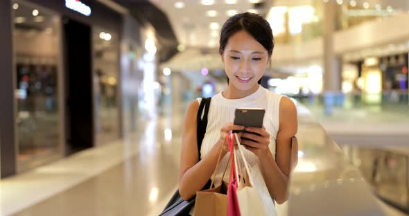 Woman using cellphone and hold paper bag