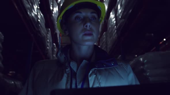 Young female worker in a warehouse at night