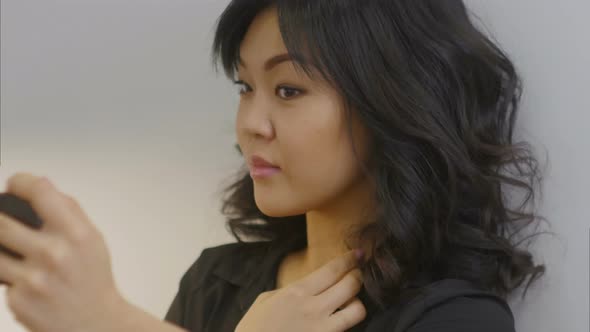 Asian Woman Using Smartphone for Correcting Her Hair and Make Up