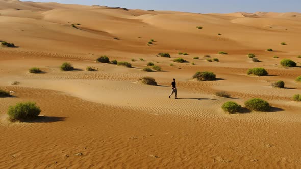 Aerial view of a man walking alone in the dunes of Sharjah desert, U.A.E.