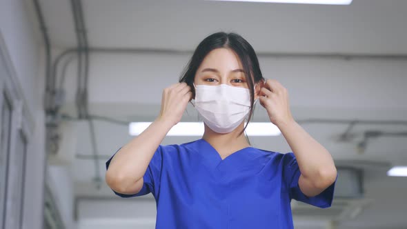 Smiling Young and Beautiful Asian Medical Nurse in Uniform at Hospital Prepared to Wear a Face Mask