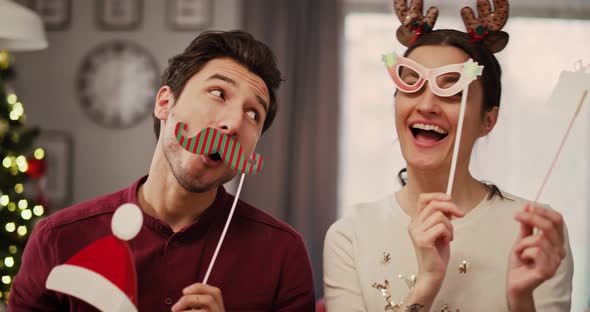 Handheld view of playful couple in Christmas masks