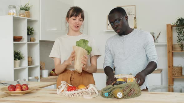 Multiethnic Couple Bringing and Unloading Groceries at Home