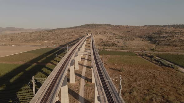 Railroad track on a bridge over a valley leading through the terrain of a hill in Israel in sunny au