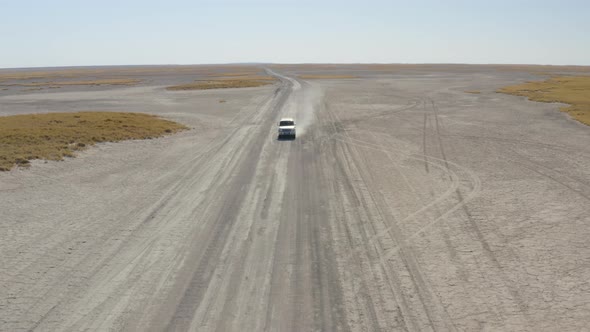 Front View Of 4x4 Car Driving On A Dusty Makgadikgadi Salt Pan On A Sunny Summer Day In Botswana. -