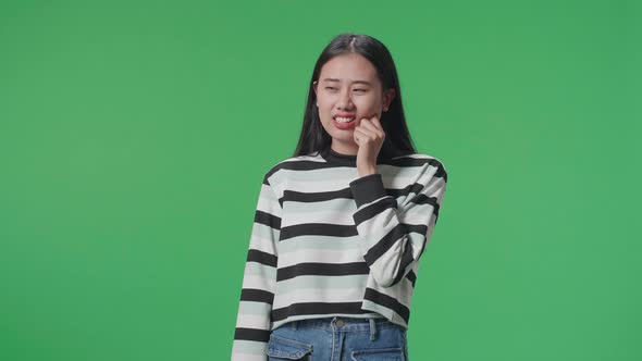 Asian Woman Having Toothache While Standing In Front Of Green Screen Background