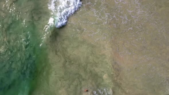 Milky, frothy seawater churns sediment with crystal clear seawater in stunning drone shot from above