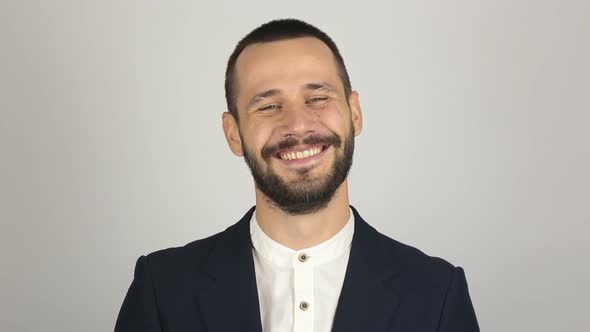 A Young Handsome Businessman in a Blue Suit Is Looking at the Camera and Laughing