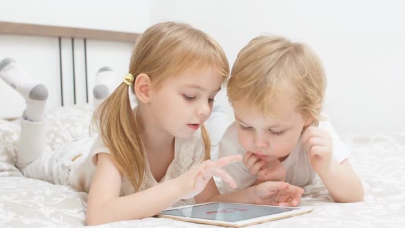 Sweet Caucasian Children Use Modern Gadget Holding Tablet in Hands