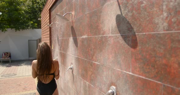 A Girl is Taking Shower After Sunbathing Outdoors