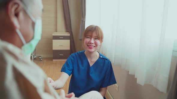 Asian beautiful nurse taking care of mature older male patient sitting on wheelchair in hospital.