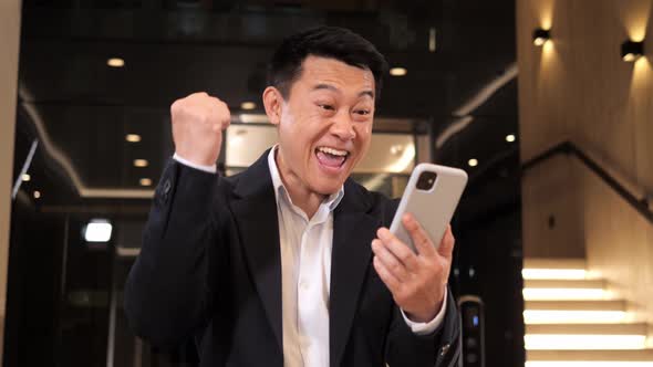 Excited Asian Male Winner Celebrating Success Mobile Phone Victory
