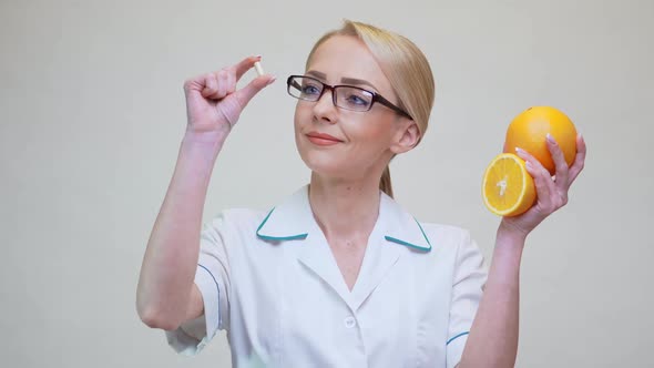 Nutritionist Doctor Healthy Lifestyle Concept - Holding Vitamin Pill and Orange Fruit