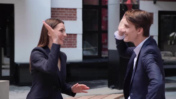 a young couple sit on a bench and chat, high-five each other