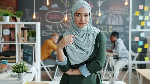 Slow Motion Portrait of Independent Muslim Entrepreneur Standing in Creative Office Holding Glasses
