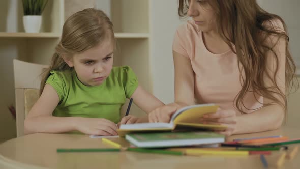 Upset Little Girl Doing School Tasks With Mother, Bored or Tired of Homework