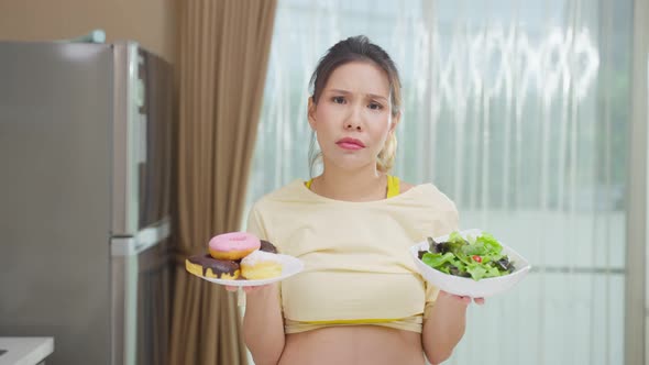 Portrait of Asian beautiful pregnant woman choosing foods on hands.