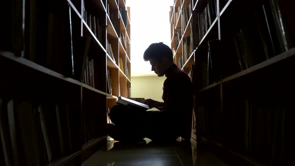 Silhouette College Student Sitting on Floor in Library