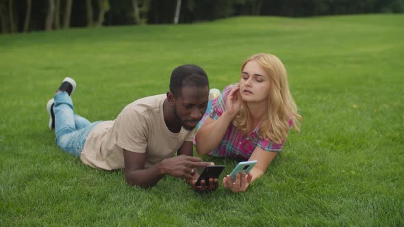 Multiethnic Family of Four Relaxing on Green Lawn