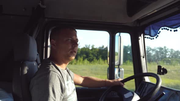 Man Holds Hand on the Steering Wheel and Driving Truck Through Countryside. Truck Driver Profile