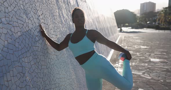 Fit african woman doing sport stretching exercise with sunset in the background